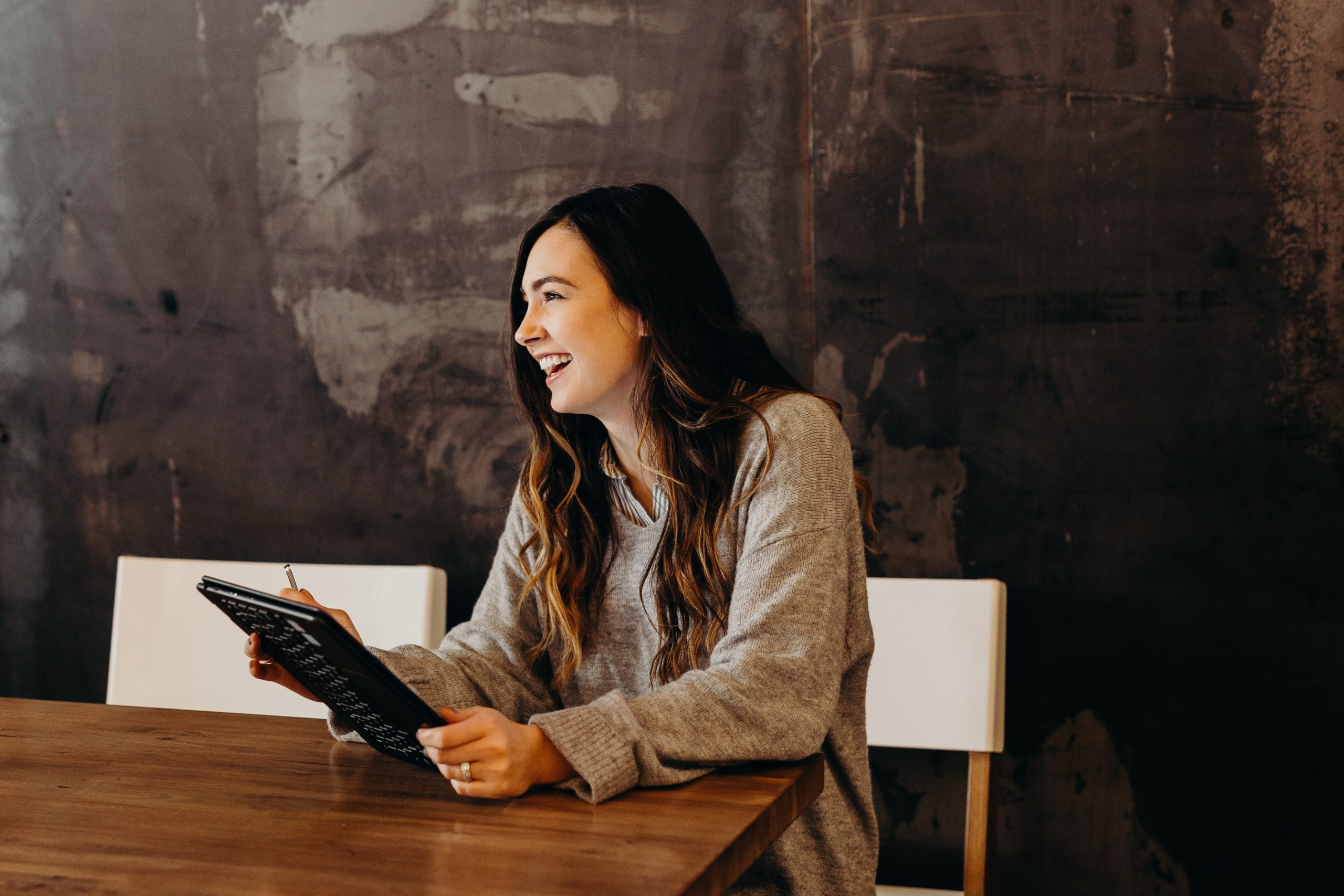 woman smiling as she holds tablet