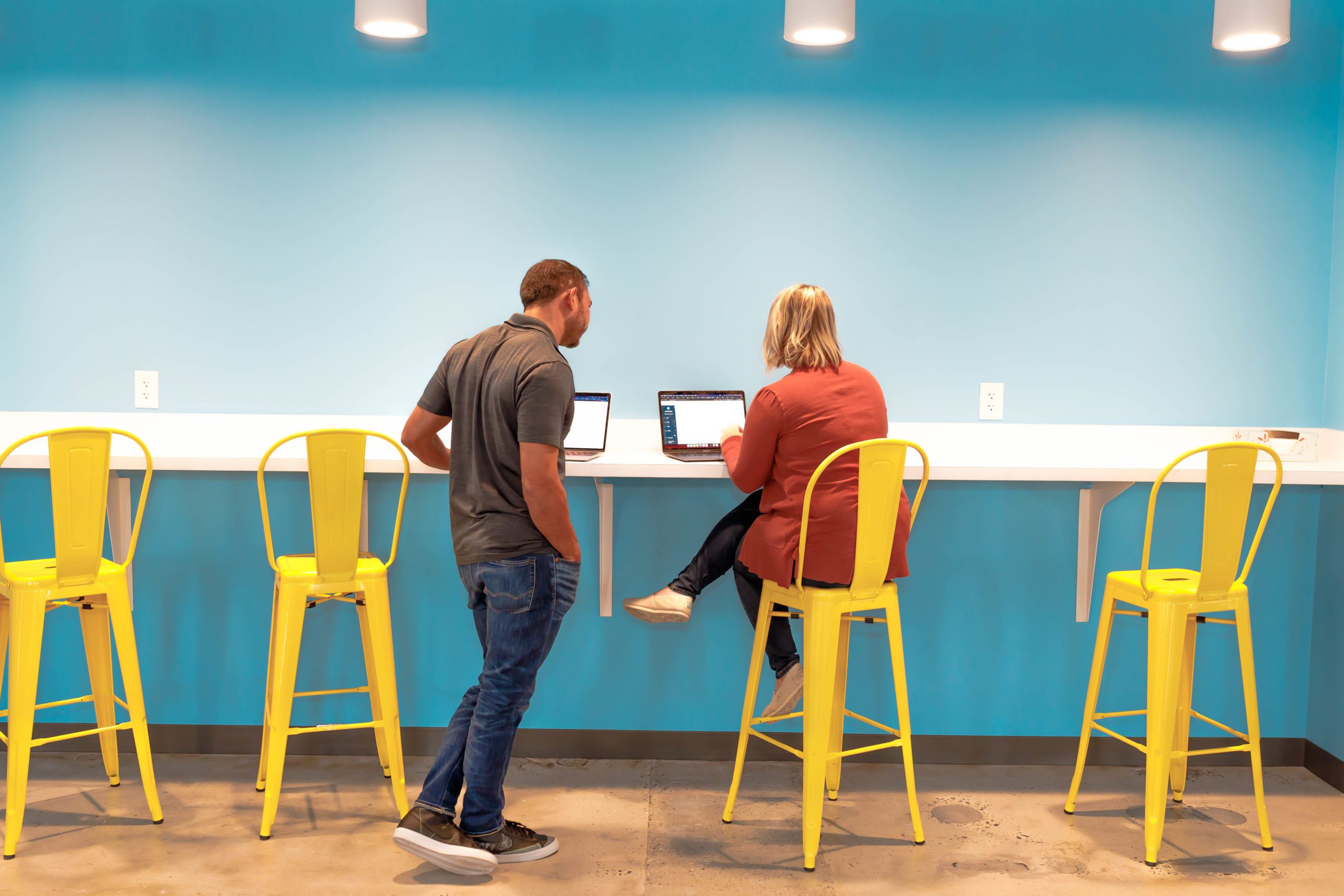 two people reviewing work on laptops