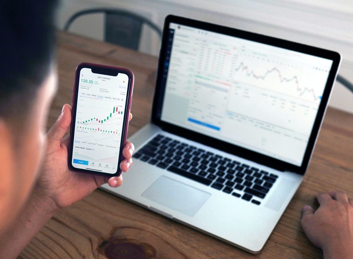 man looking at charts on phone and computer