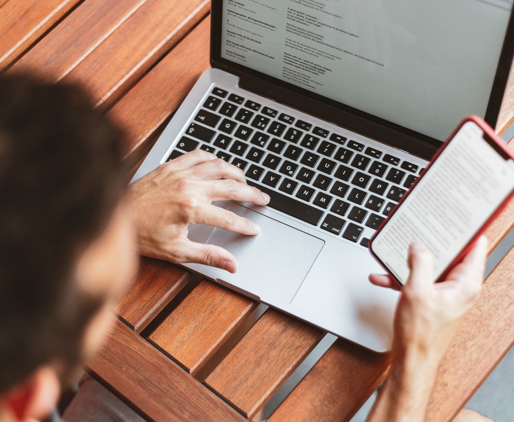 Man reading iPhone in front of computer.