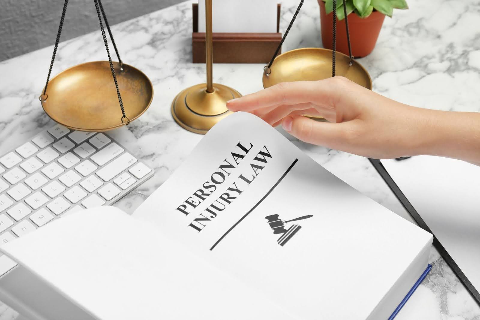 A person's hand turning a page in a book titled 'PERSONAL INJURY LAW.'