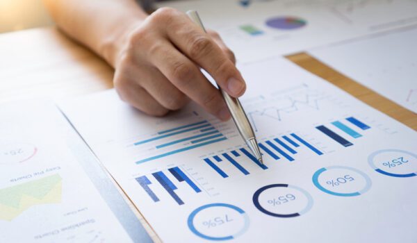 hand holding pen pointing at graph data on a piece of paper