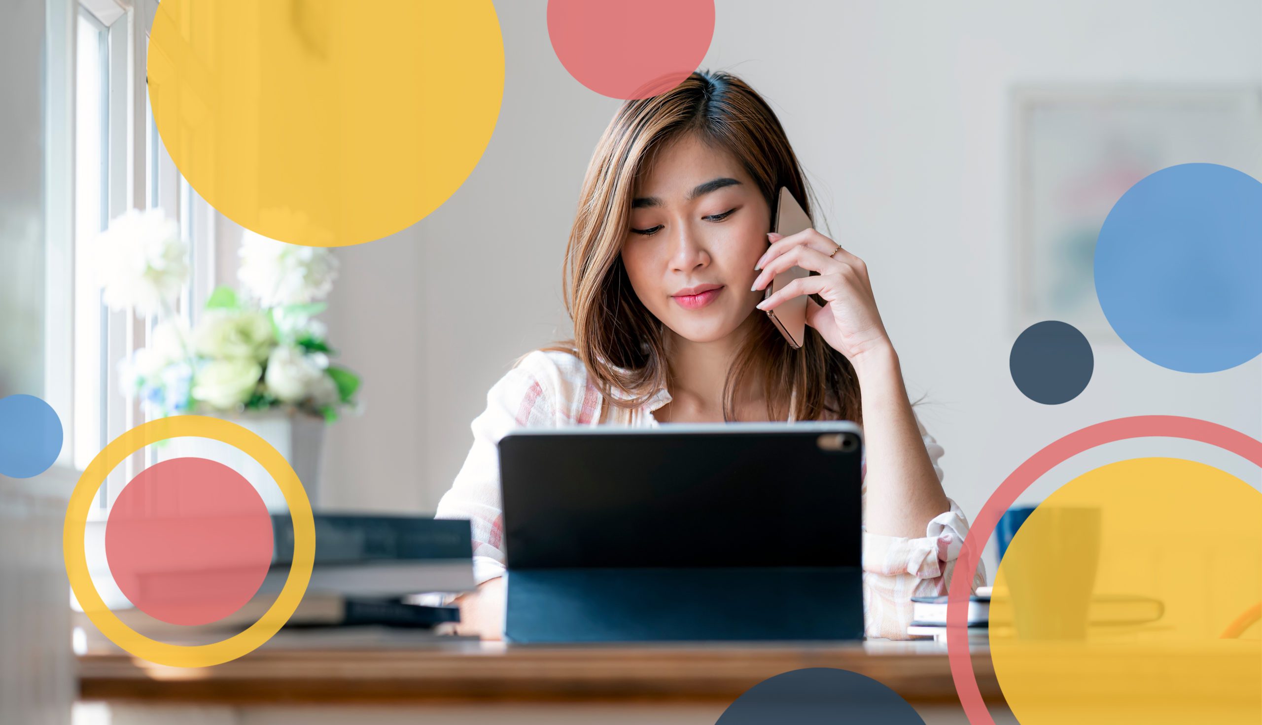 woman on her phone while working on her computer