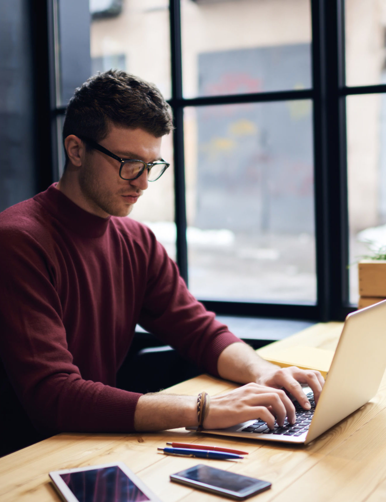 Man with glasses typing text on laptop