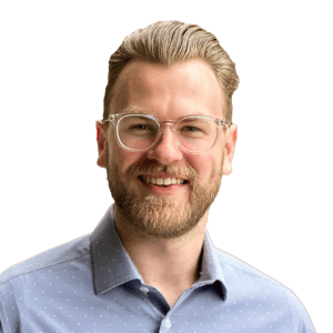 Blonde man with clear classes, a beard, and a grey polo shirt.